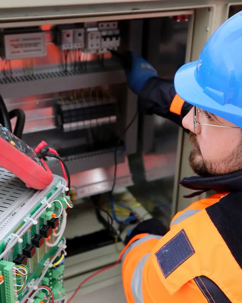 Técnico con casco comprobando un cuadro eléctrico con un polímetro